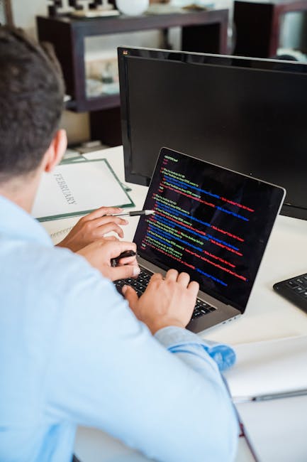 A close-up view of a computer screen displaying lines of colorful programming code, including keywords, variables, and functions in various shades of pink, blue, green, and white on a dark background.